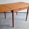 Compact teak dining table with extensions opened
