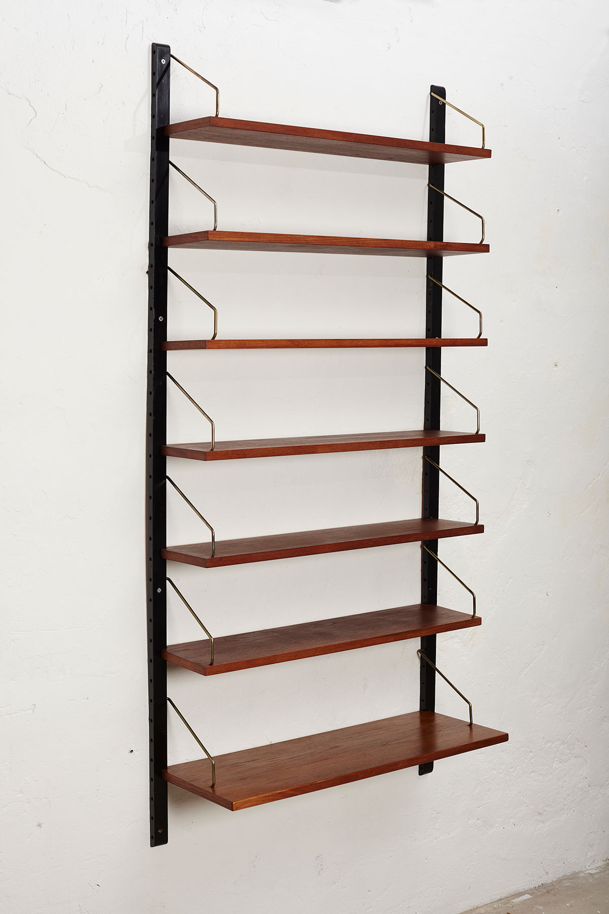 Danish wall unit with seven shelves made from teak installed on a white wall